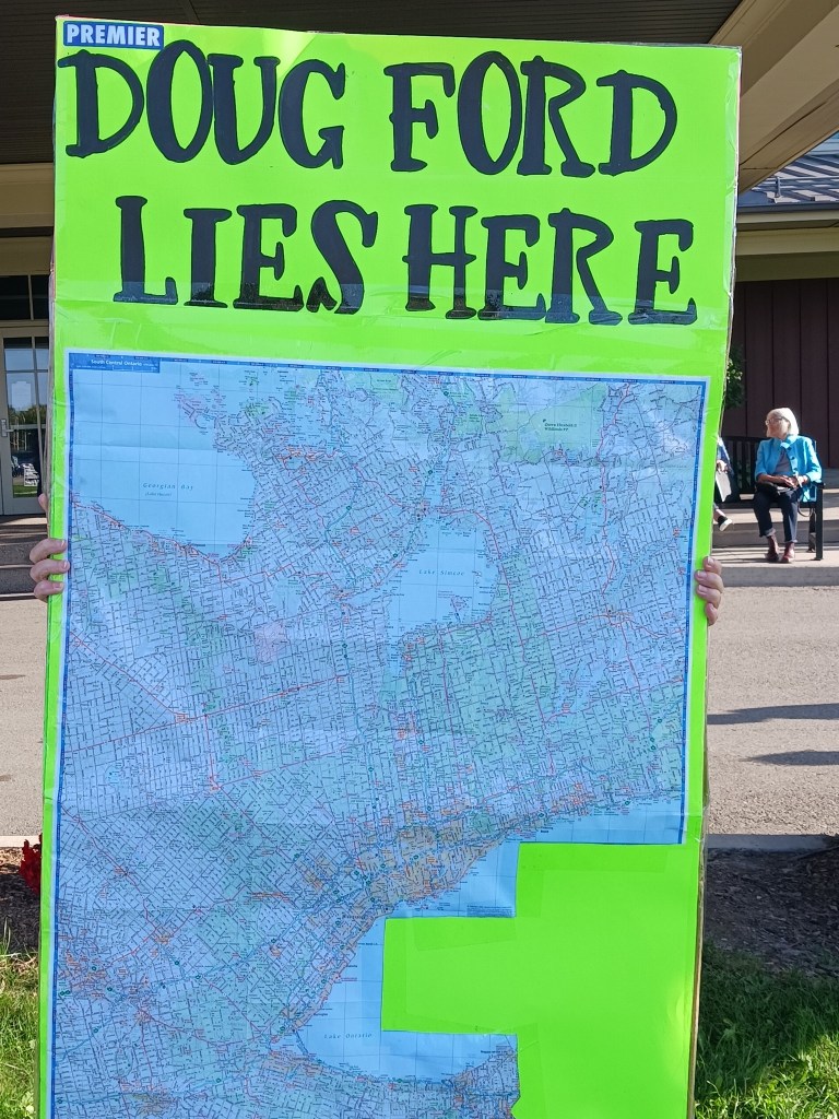 Poster saying "Doug Ford Lies Here" and is the facebook group photo.

