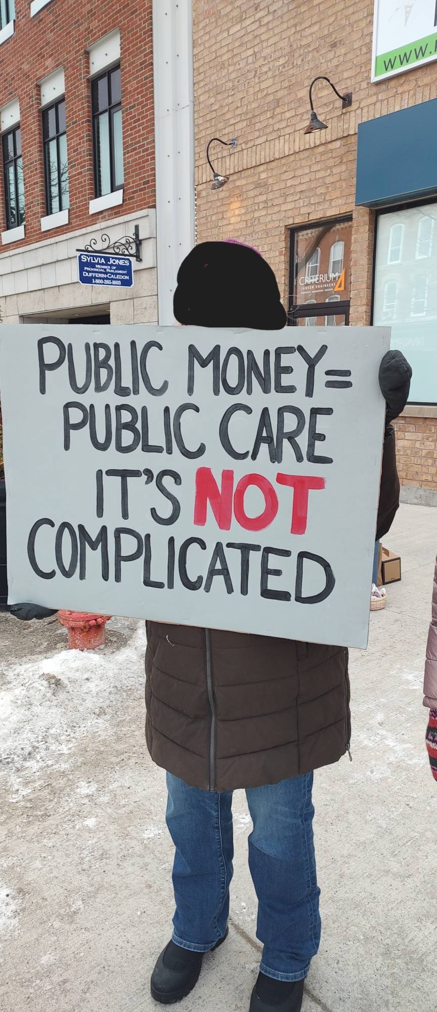 protest poster "public money = public care. It's not complicated"